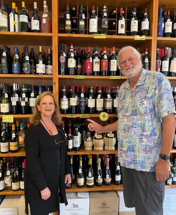 Anita and Tony Matlock standing in front of shelves filled with wine bottles inside a wine shop.